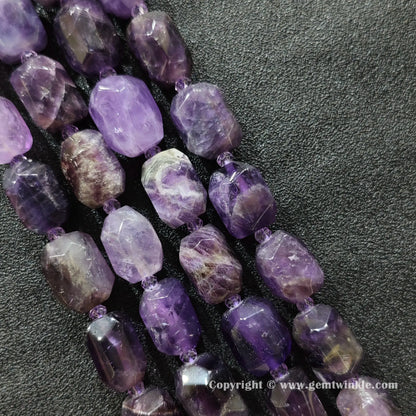 multiple strands of chunky amethyst faceted barrel beads on dark fabric surface