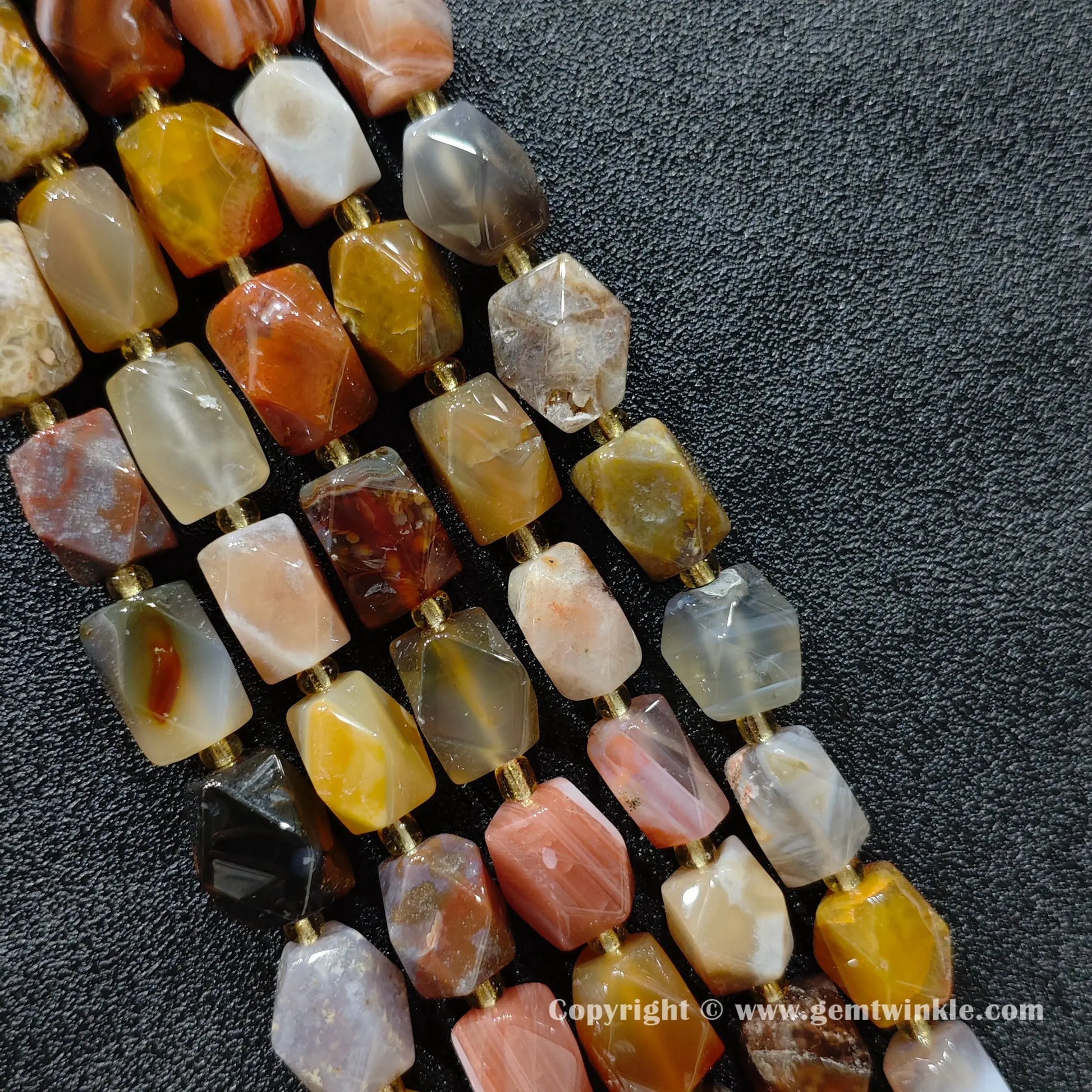 multiple strands of earthy faceted ocean agate barrel beads on dark texture