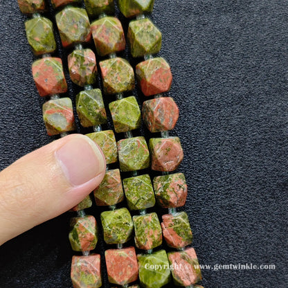 multiple strands of faceted unakite barrel beads held in hand