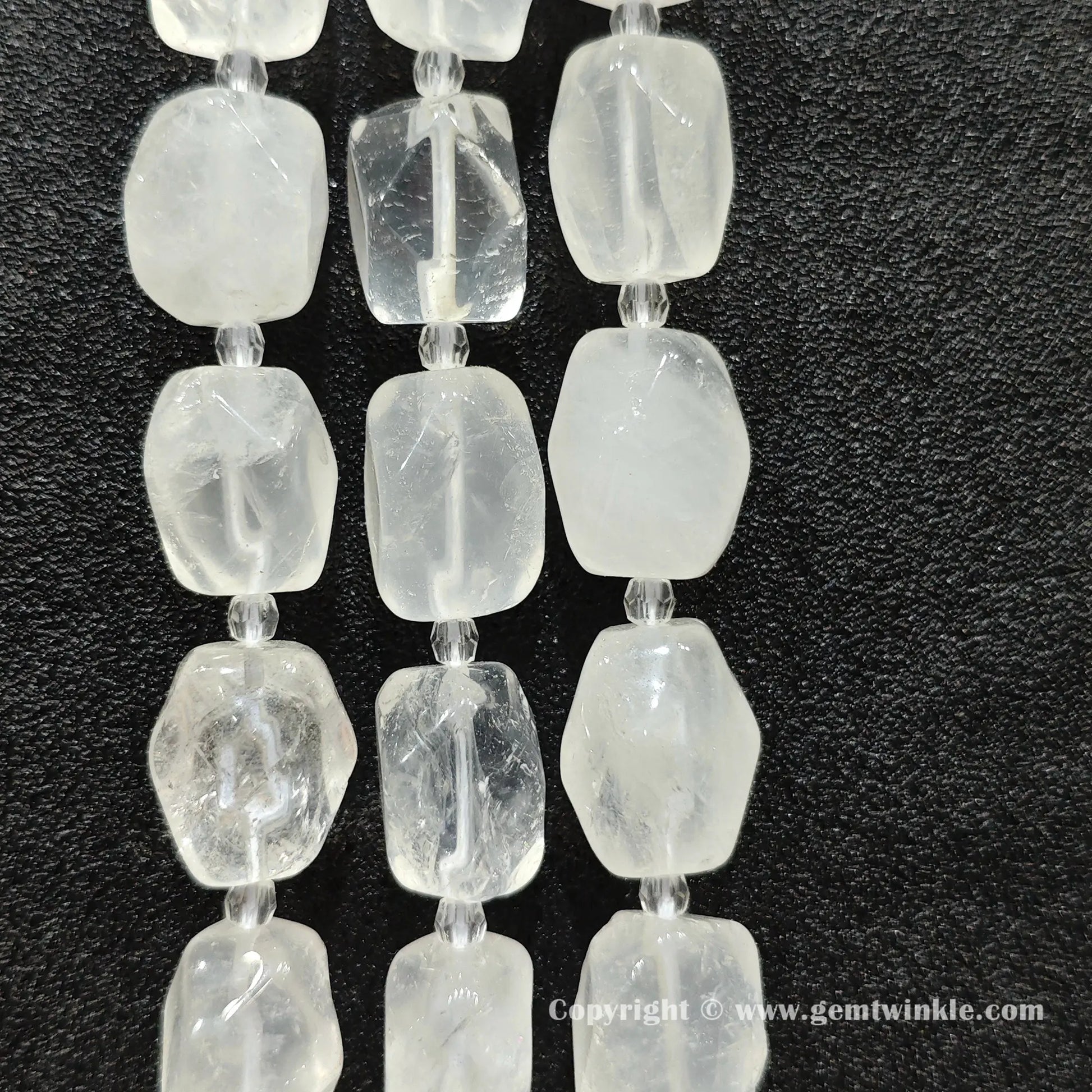 multiple strands of frosty clear quartz faceted barrel beads on dark texture