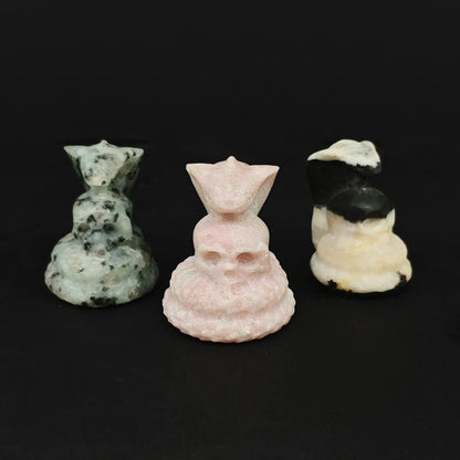 Assorted natural stone cobra skull figurines in pink opal, speckled green stone, and zebra patterned stone for gothic curio wholesale