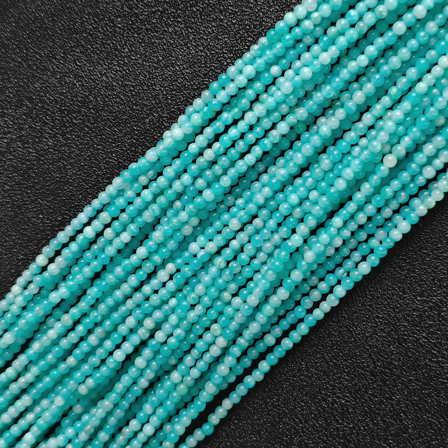 Macro view of natural amazonite 3mm micro seed round beads displaying icy turquoise aqua-cyan tones and feldspar sheen