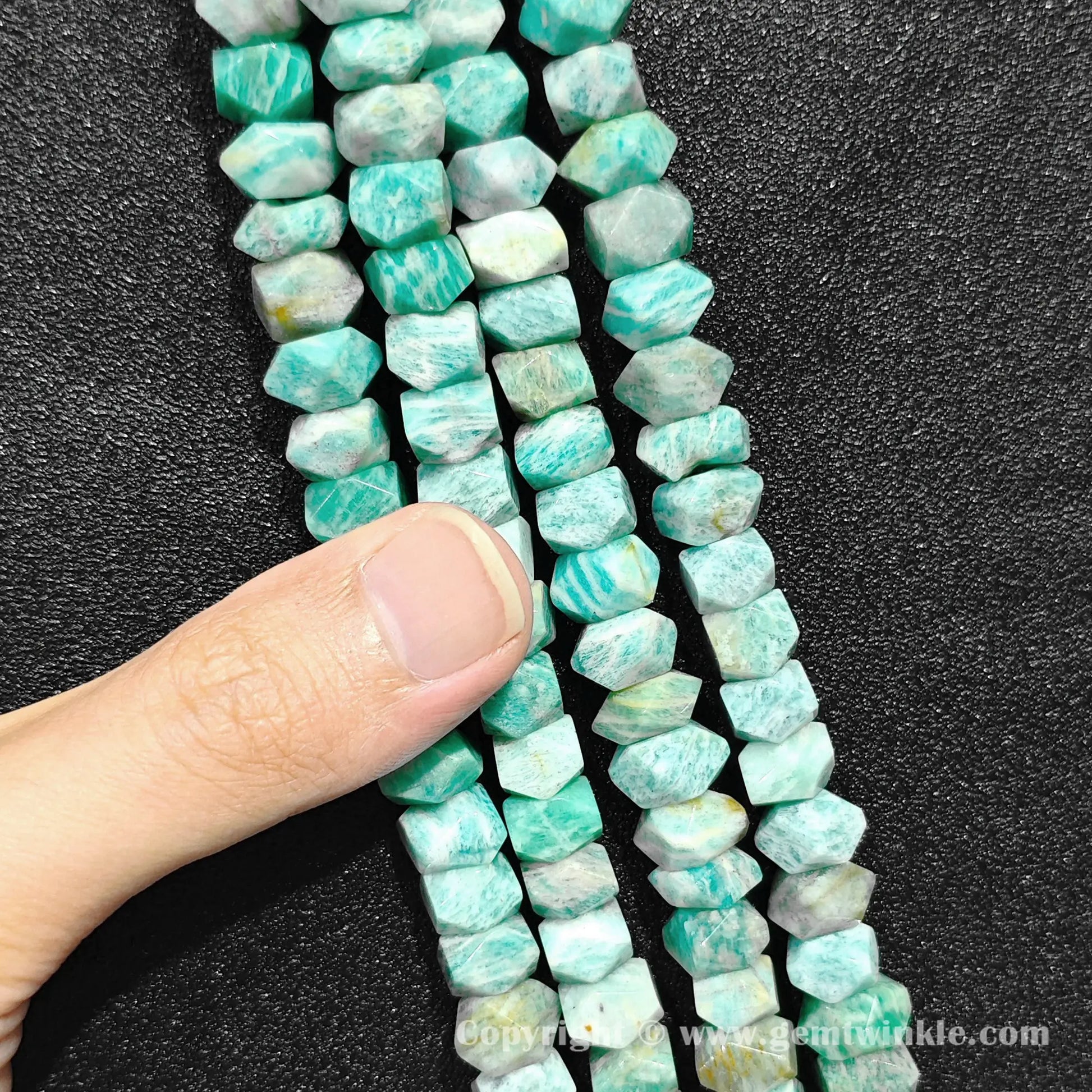 Hand inspecting 35cm strand of natural mint green amazonite 10x6mm column beads