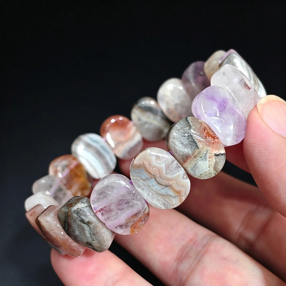 Hand holding a natural amethyst agate slice bracelet featuring purple banding and earthy tones for wholesale buyers