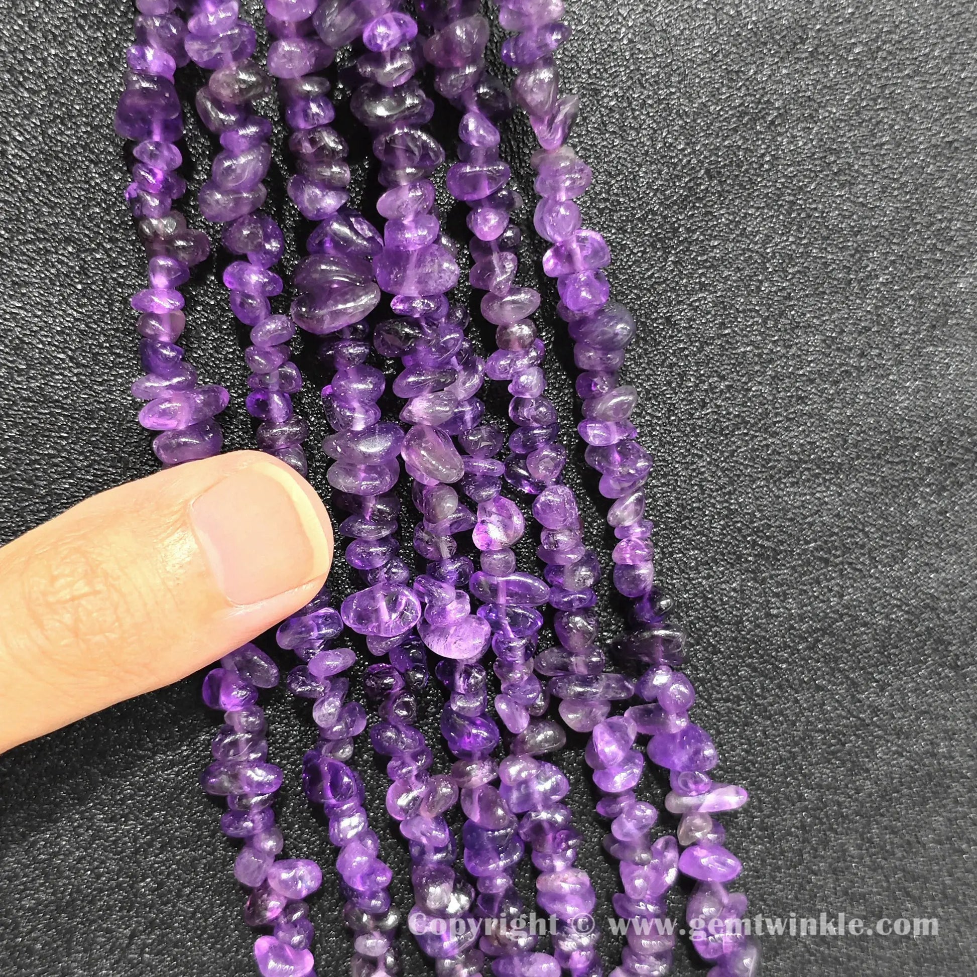 Hand holding 75cm continuous strand of natural amethyst irregular chip beads