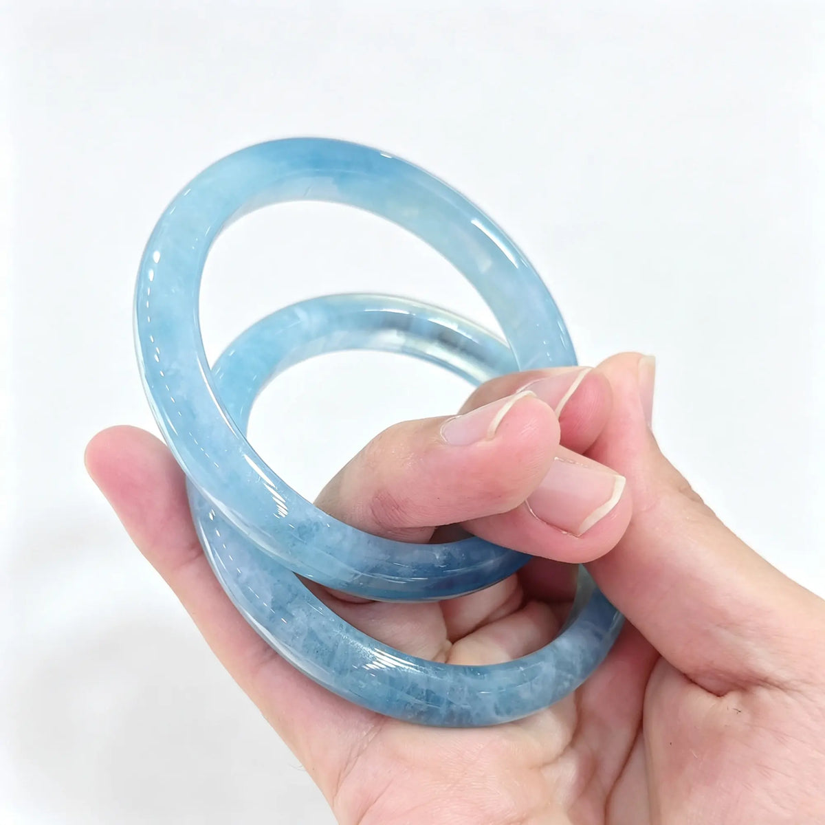 Natural Aquamarine solid gemstone bangle bracelet held on hand displaying refreshing ice blue tones