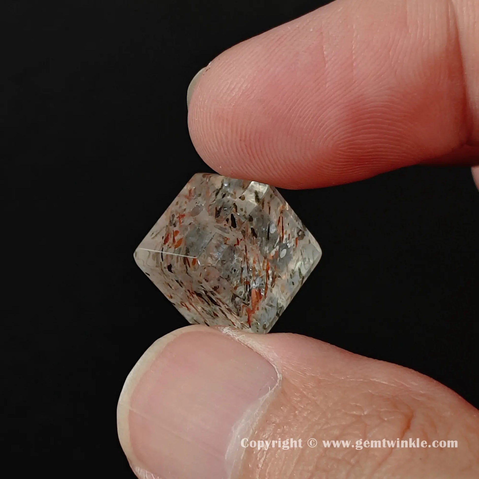 Hand holding a 12mm natural black gold quartz square bead showing internal lepidocrocite needles