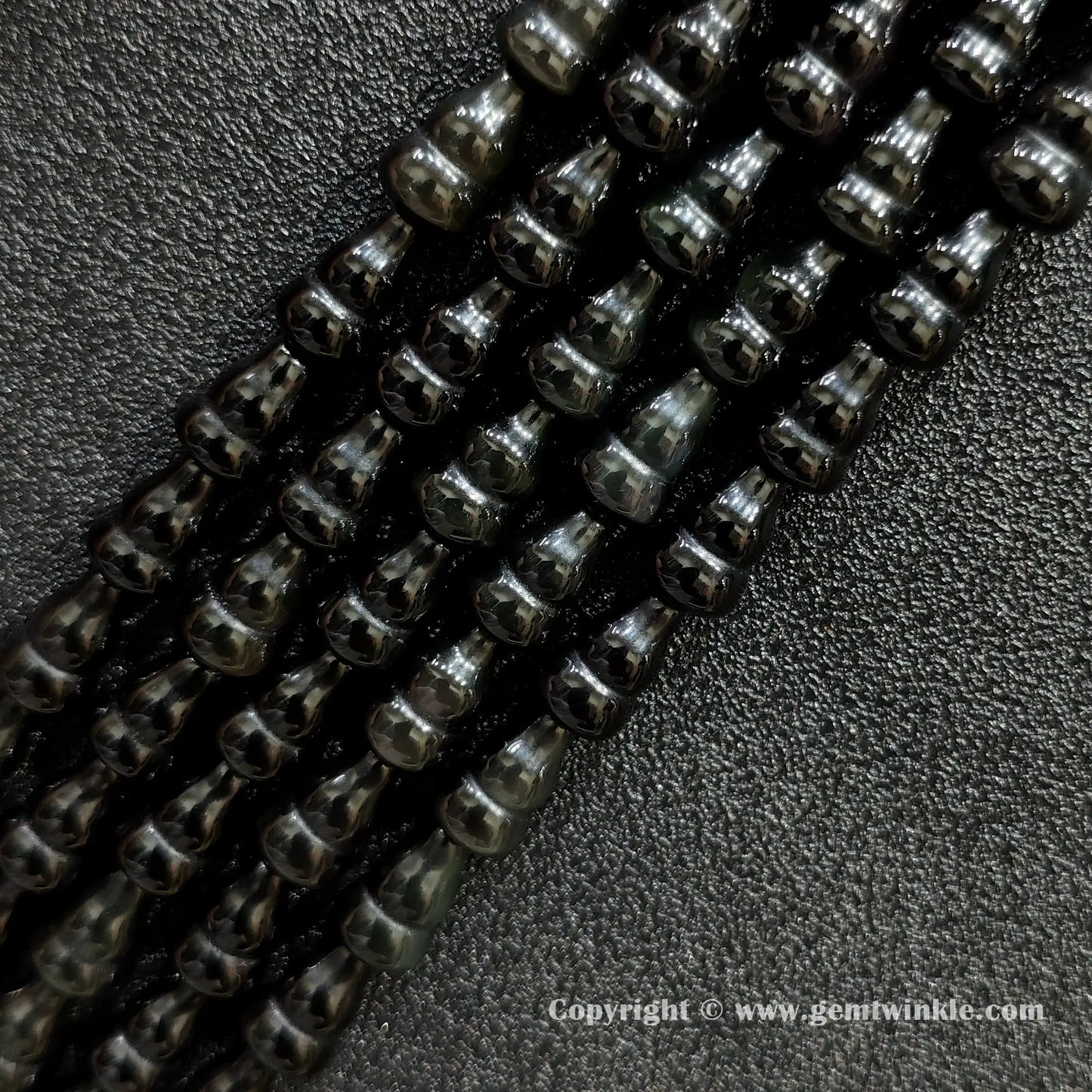 Angled view of natural black obsidian calabash cut gemstone strands