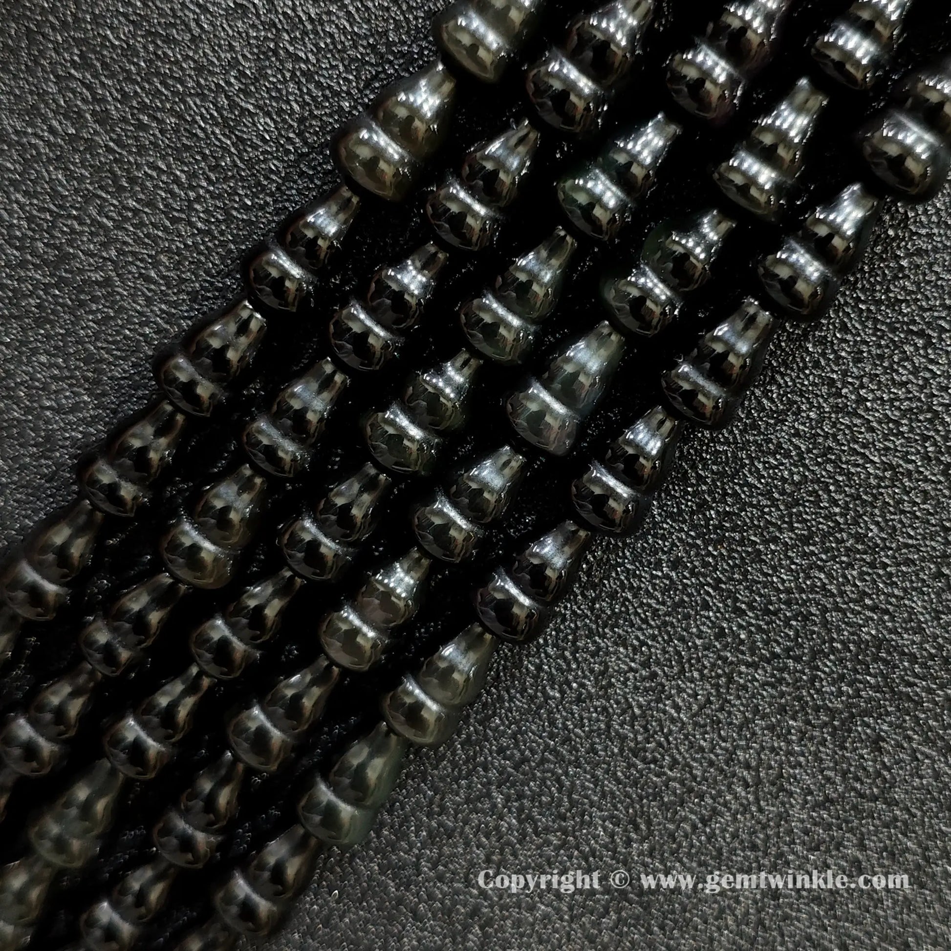 Angled view of natural black obsidian calabash cut gemstone strands