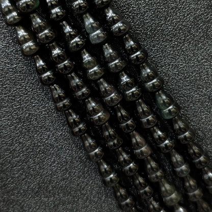 Macro closeup of natural black obsidian gourd beads showing smooth polish and calabash shape