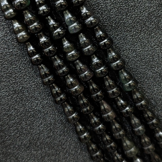 Macro closeup of natural black obsidian gourd beads showing smooth polish and calabash shape