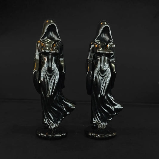 Two 10cm natural black obsidian shrouded goddess statues with flowing cloaks standing front facing against a dark background
