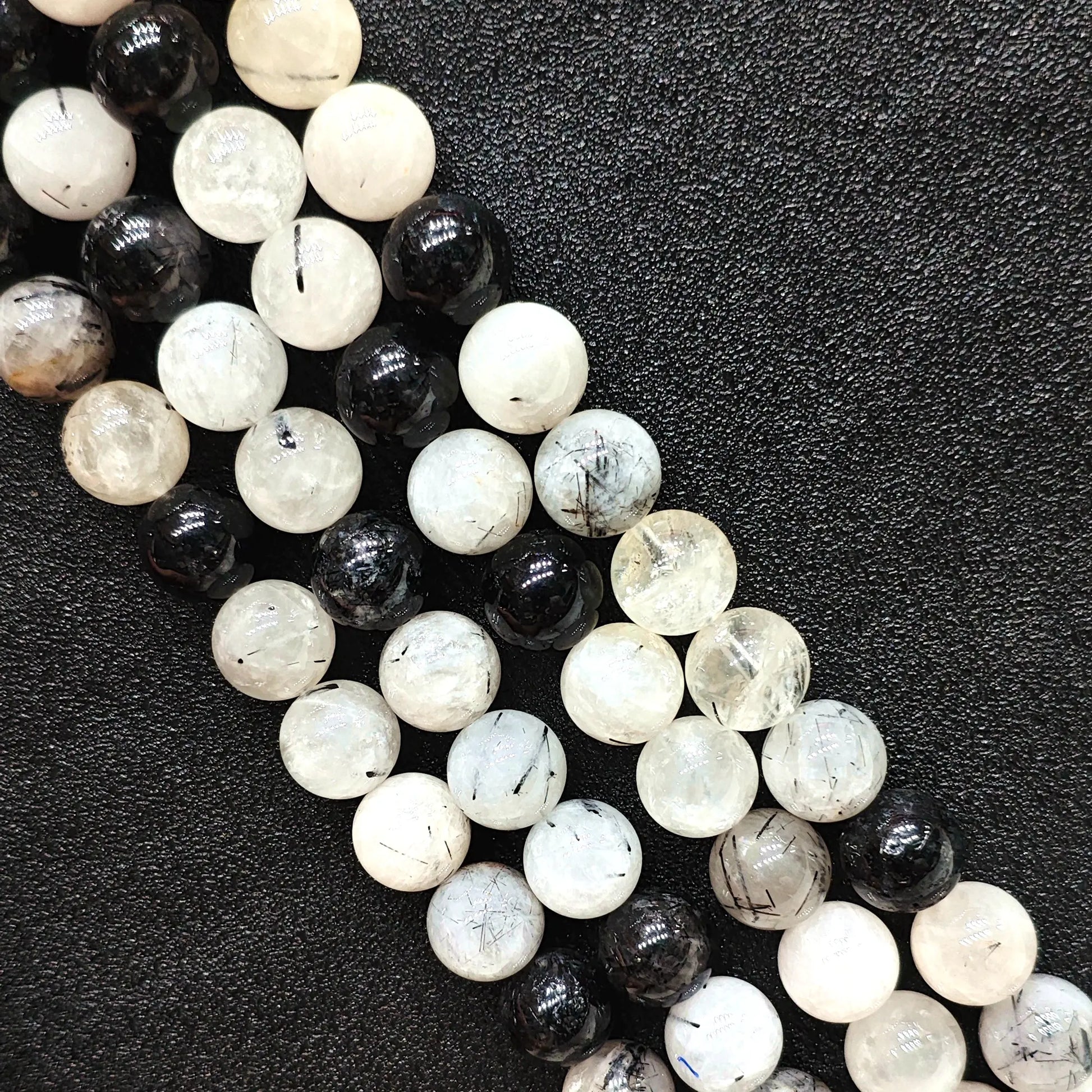 Close up look of C grade natural black rutilated quartz strands showing heavy internal inclusions and tourmaline needles on a dark background