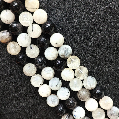 Close up look of C grade natural black rutilated quartz strands showing heavy internal inclusions and tourmaline needles on a dark background