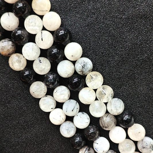 Close up look of C grade natural black rutilated quartz strands showing heavy internal inclusions and tourmaline needles on a dark background