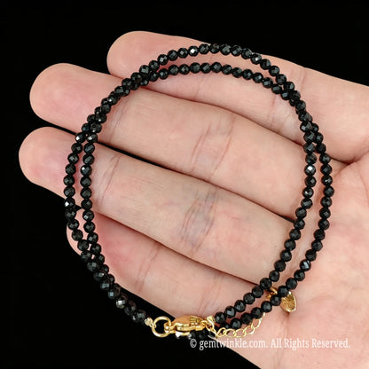 single strand black tourmaline collar necklace coiled across palm showing glassy luster