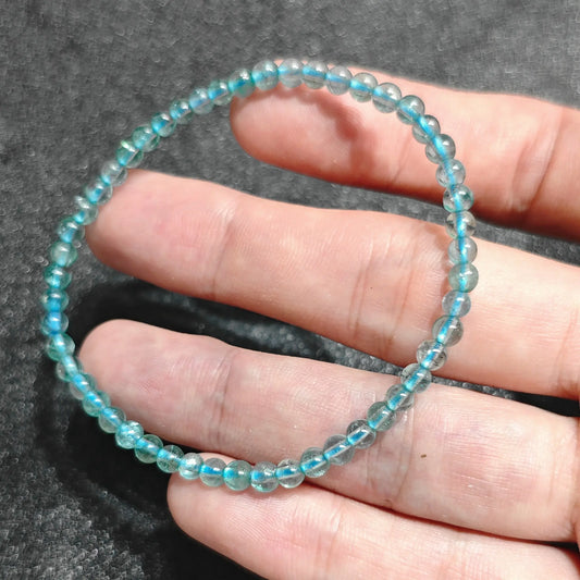 4mm natural blue fluorite smooth round bead stretch bracelet held in hand showing ocean blue translucency and glossy surface