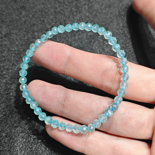 Natural blue topaz faceted mini bead bracelet held in hand showing vibrant sky blue tones and crisp sparkling facets