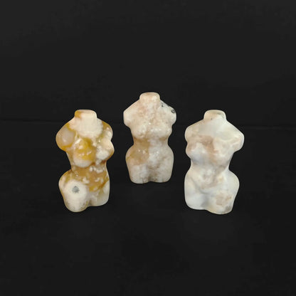 Three natural flower agate goddess torso figurines standing together on a black background displaying unique pink and white floral patterns