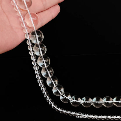 Multiple strands of natural clear quartz round loose beads held in hand, perfect supplies for handcrafted jewelry maker