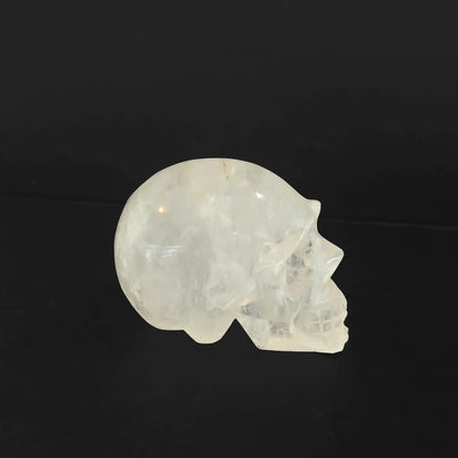 Natural clear quartz skull carving showing milky opaque texture and heavy internal cotton-like inclusions on black background