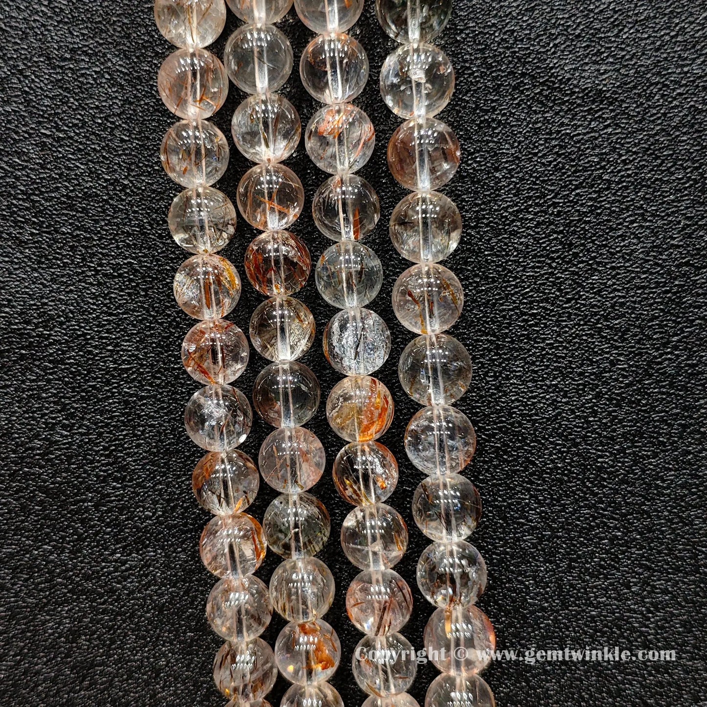 Detailed shot of real copper hair quartz round beads displaying transparent crystal bodies and un-dyed metallic inclusions for bracelet making