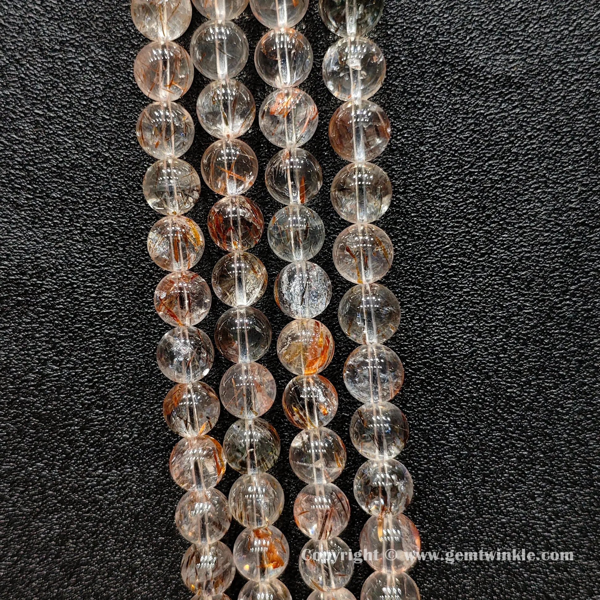 Detailed shot of real copper hair quartz round beads displaying transparent crystal bodies and un-dyed metallic inclusions for bracelet making