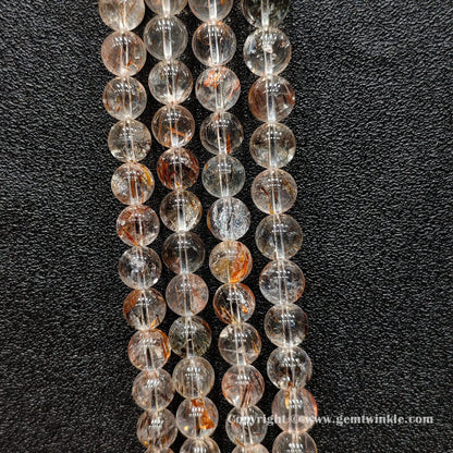 Detailed shot of real copper hair quartz round beads displaying transparent crystal bodies and un-dyed metallic inclusions for bracelet making
