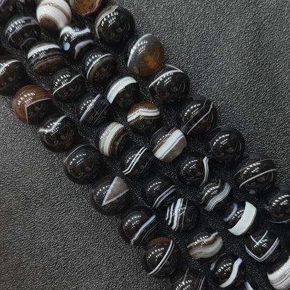 Natural dark brown banded agate round loose beads strands showing crisp striped orbital patterns on a dark background for jewelry making