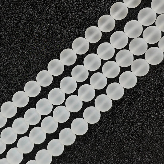 Natural frosted clear quartz matte crystal beads strands arranged diagonally on black background