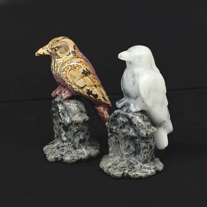 Two 3 inch hand carved natural gemstone gothic raven statues perched on cross tombstone bases made of speckled granite rock on a dark background