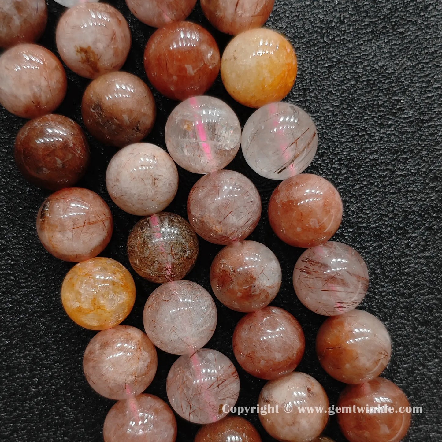 Detailed shot of real red rutilated quartz crystal beads with natural structural veils strung on soft pink jewelry cords