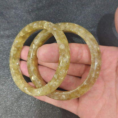 Natural Golden Mica solid gemstone bangle bracelets showing shimmering champagne gold flash held on hand