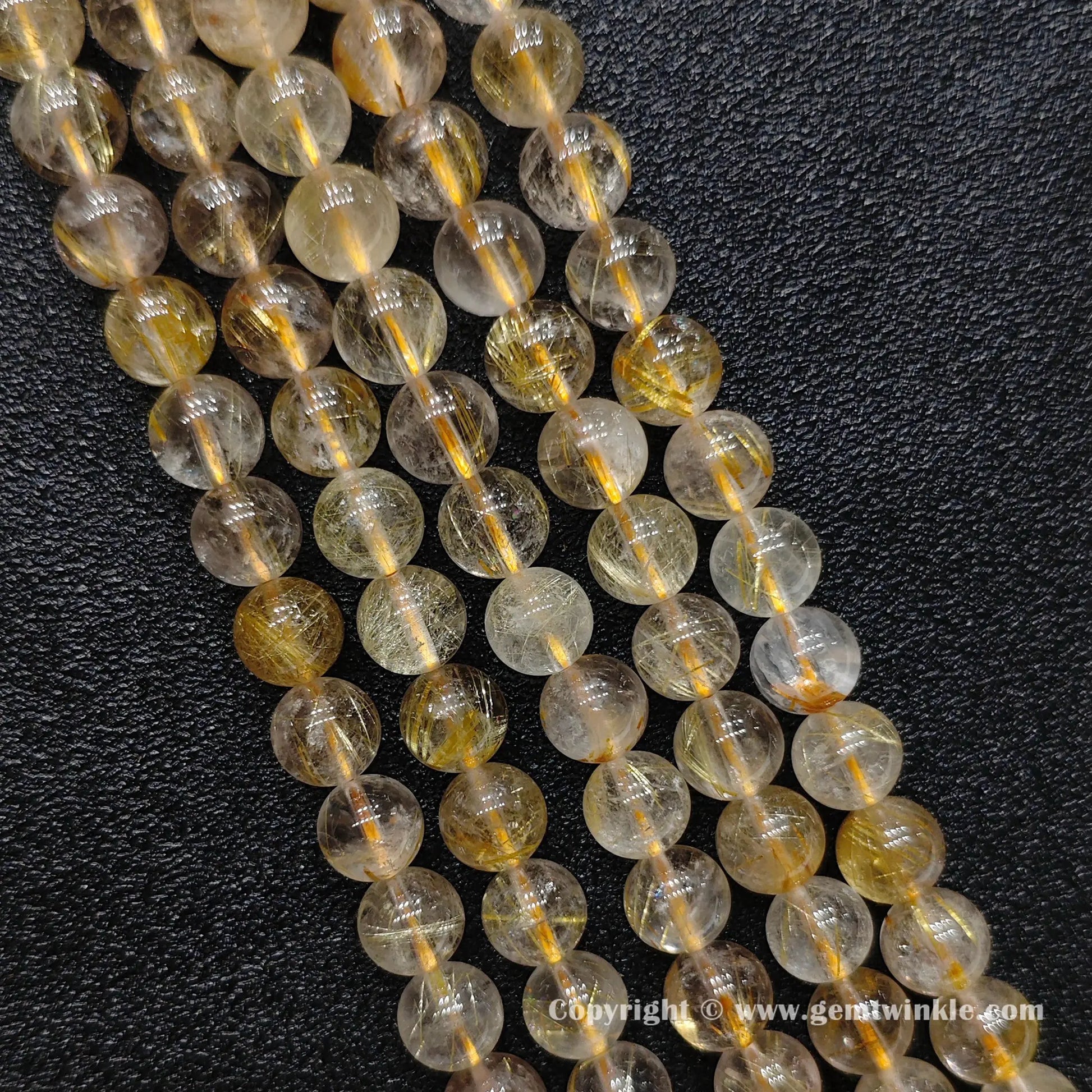 Detailed perspective of commercial grade 8mm gold hair quartz beads with natural internal crystal mist strung on jewelry wire