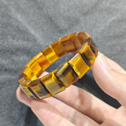 Hand holding a natural golden yellow tiger eye plate bead bracelet with silky optical chatoyancy