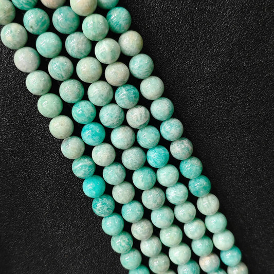 Natural Grade C amazonite round gemstone beads close up showing yellowish mineral matrix and white feldspar