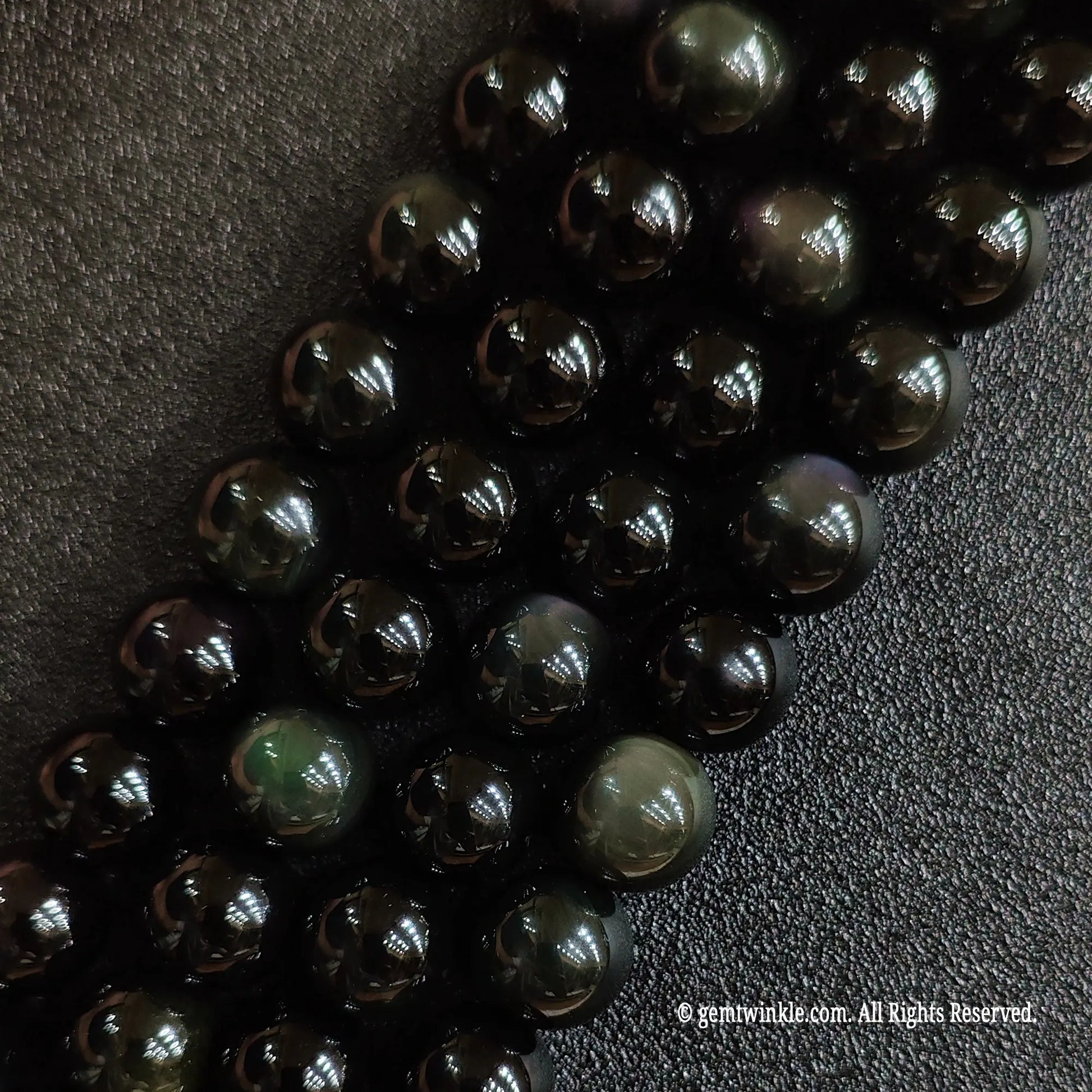 Close up view of natural rainbow obsidian crystal beads highlighting distinct circular green eye shimmer