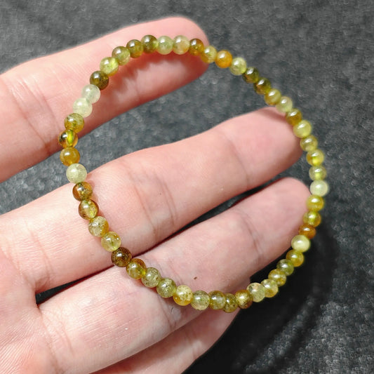 4mm natural green garnet smooth round bead stretch bracelet held in hand showing translucent olive green color and polished luster