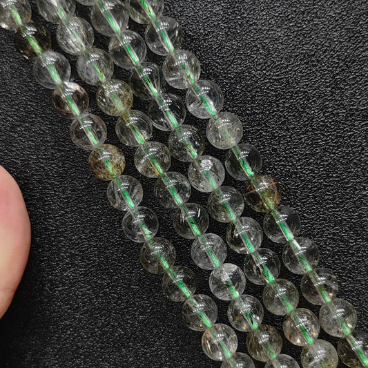 Natural green rutilated quartz 6mm beads strand showing needle-like green inclusions on dark background