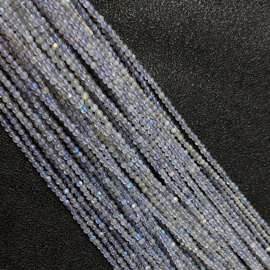 Macro closeup of natural grey blue moonstone micro round beads showing electric blue schiller flash and translucent texture