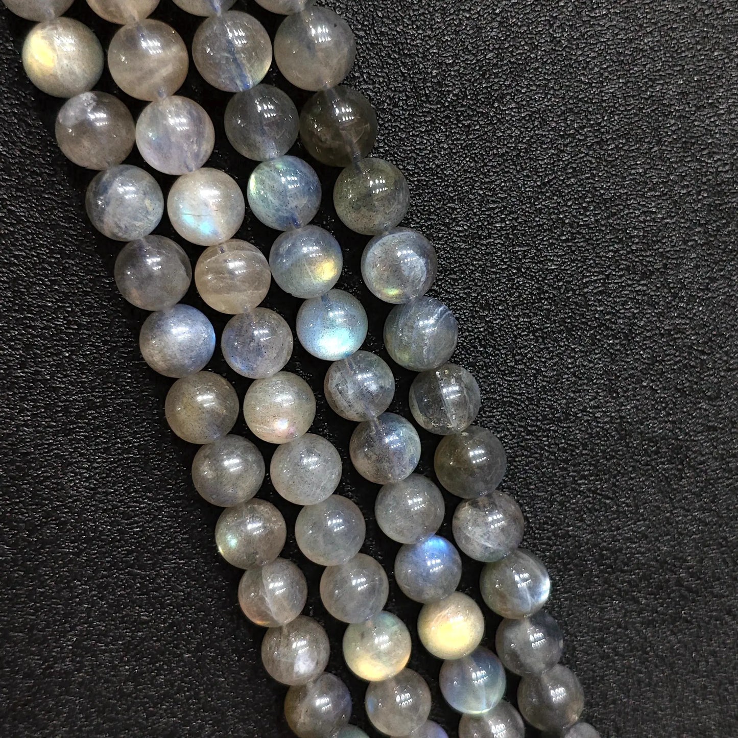 Macro closeup of natural grey moonstone round beads showing blue schiller flash and smoky feldspar texture