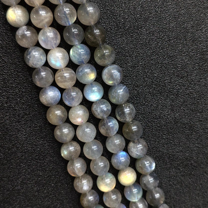 Macro closeup of natural grey moonstone round beads showing blue schiller flash and smoky feldspar texture