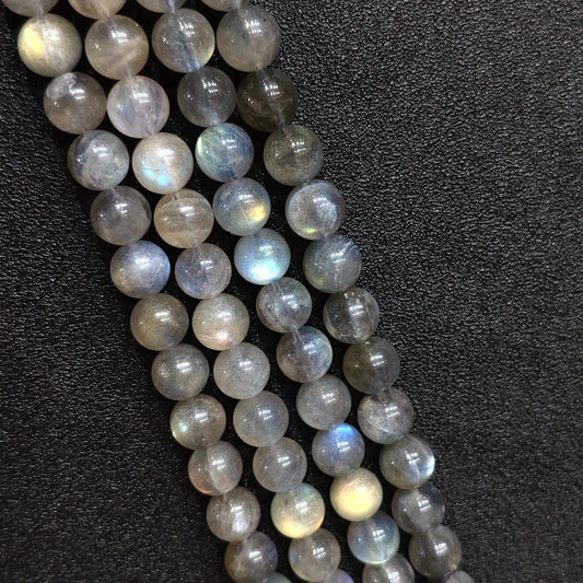 Macro closeup of natural grey moonstone round beads showing blue schiller flash and smoky feldspar texture