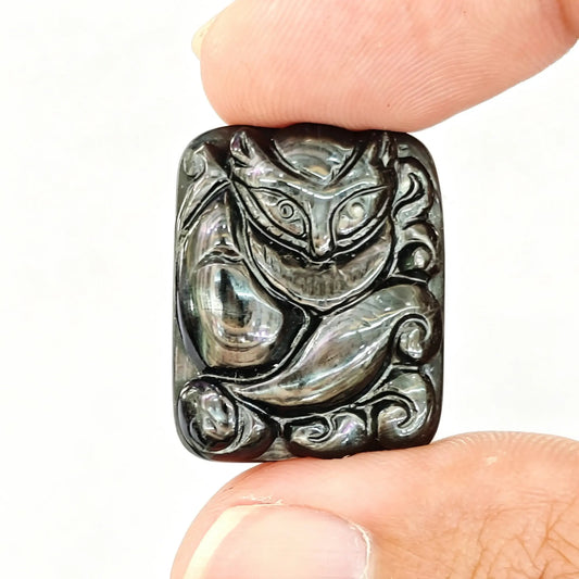 Natural hypersthene carved fox pendant held between fingertips showing black metallic gold sheen and intricate tail relief