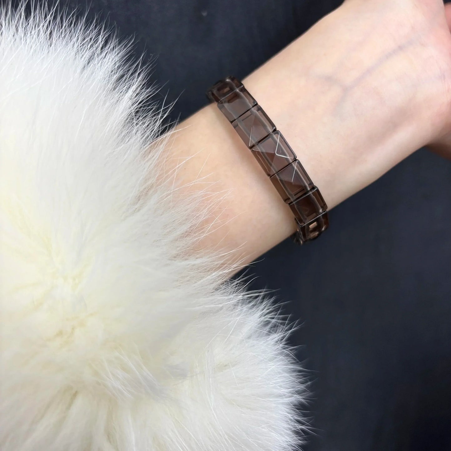 Model wearing a Gem's Twinkle rectangle bead obsidian bracelet with a white fur coat.