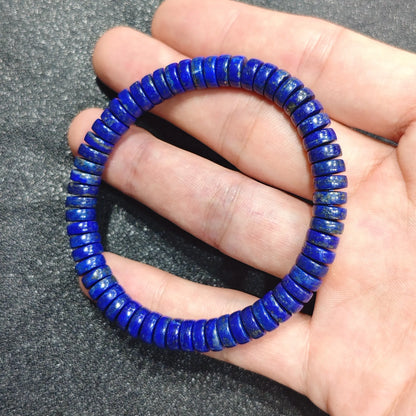 Close up view of a hand holding a natural lapis lazuli bracelet crafted from 7x3mm royal blue abacus rondelle beads