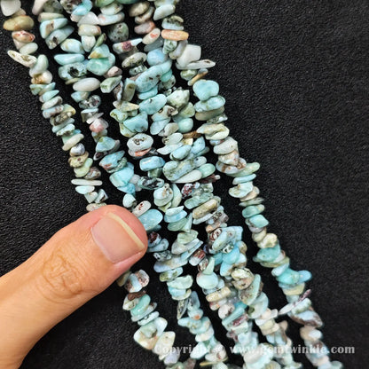 Hand holding 35cm strand of natural blue larimar 5-10mm irregular chip beads