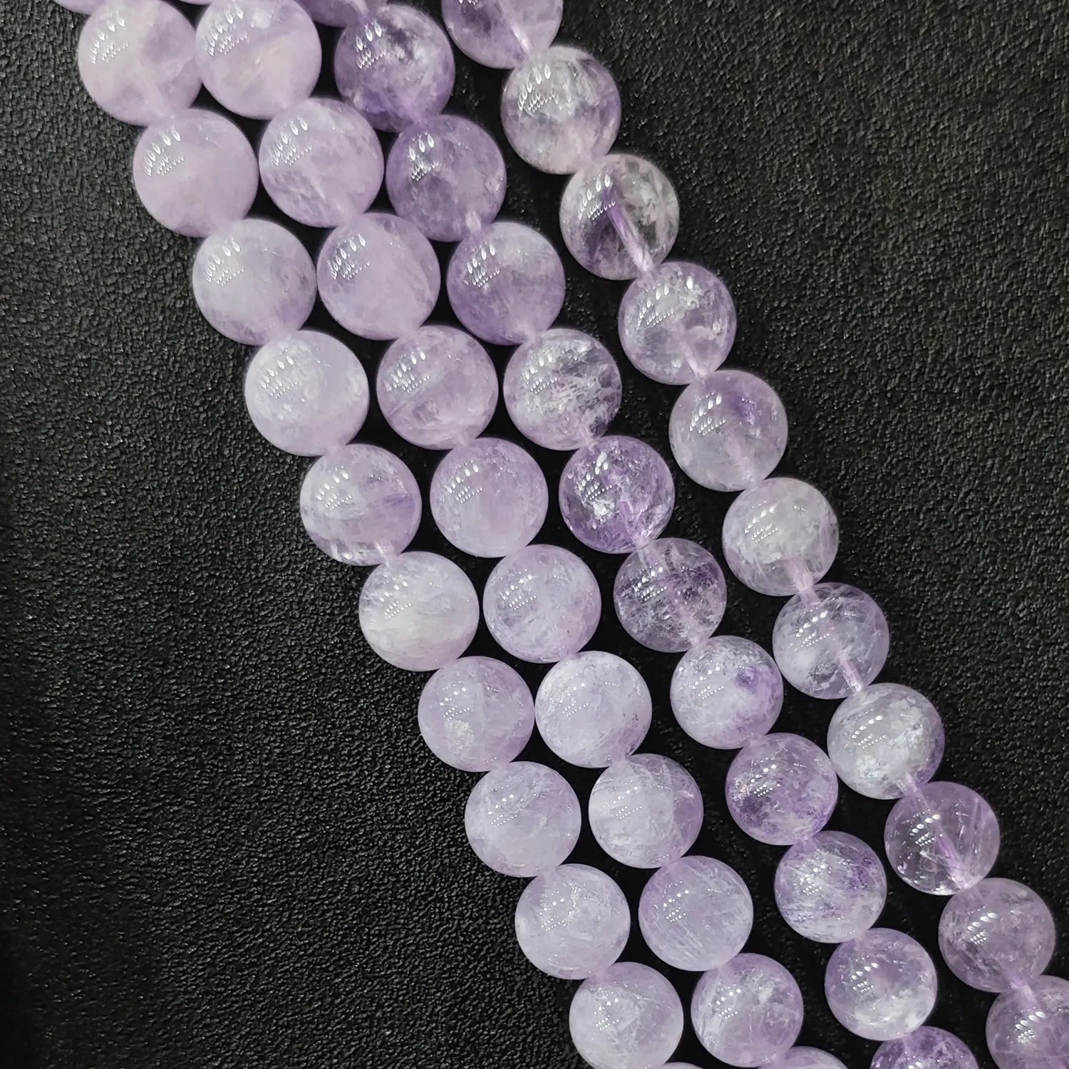 Close up view of natural lavender amethyst loose round beads strands in light lilac pastel quartz tones