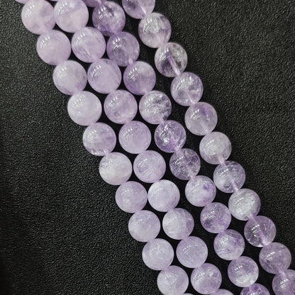 Close up view of natural lavender amethyst loose round beads strands in light lilac pastel quartz tones