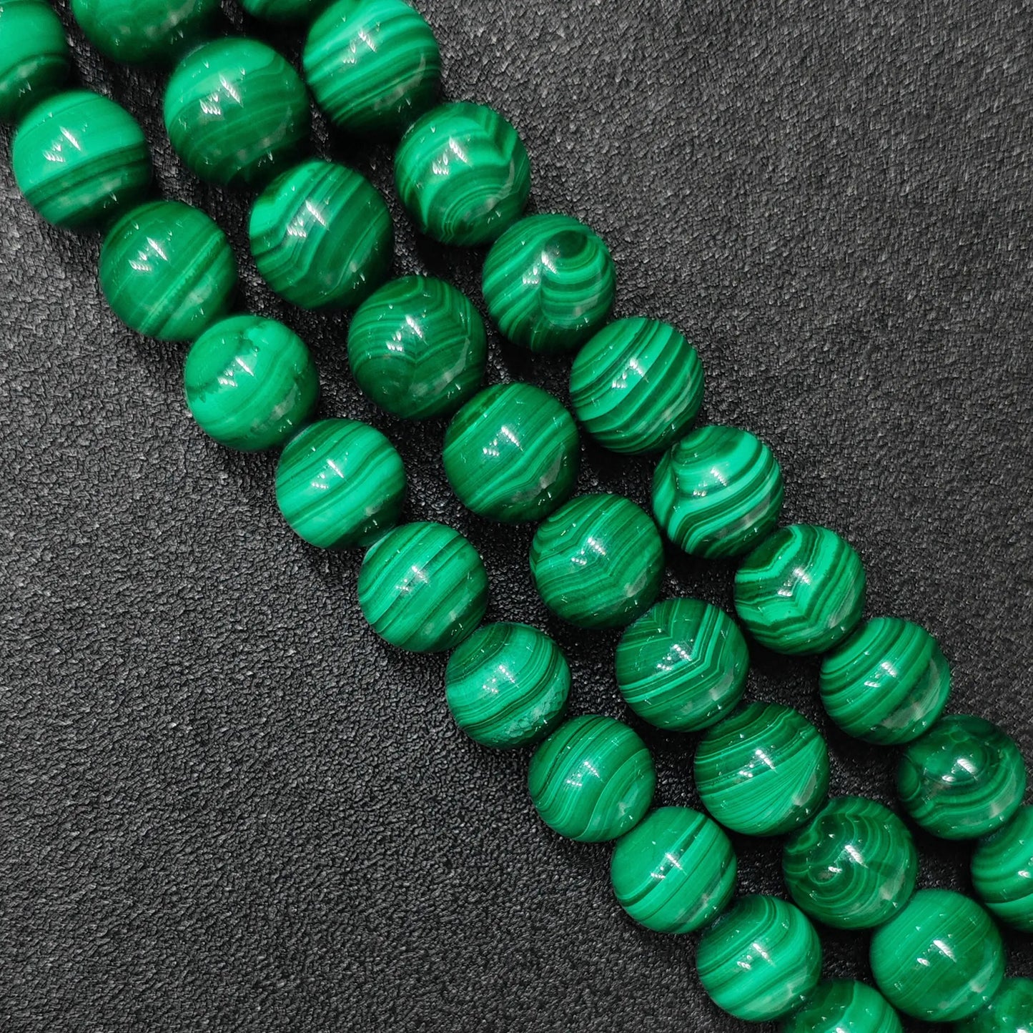 Natural malachite crystal beads image_d1605d.jpg displaying vibrant green concentric bands on polished round strands